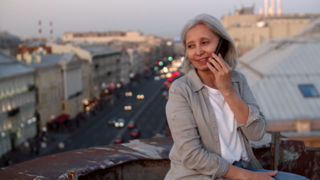 Gutaussehende-ältere-Frau-im-Telefon-auf-dem-Dach