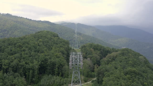 Drone-view-ropeway-in-green-mountain.-Cable-car-cabin-moving-on-ropeway-in-mountain-resort-at-summer.-Aerial-landscape-cable-car-way-in-mountain-covered-summer-forest
