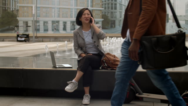Asian-Woman-Having-Phone-Call-Outdoors