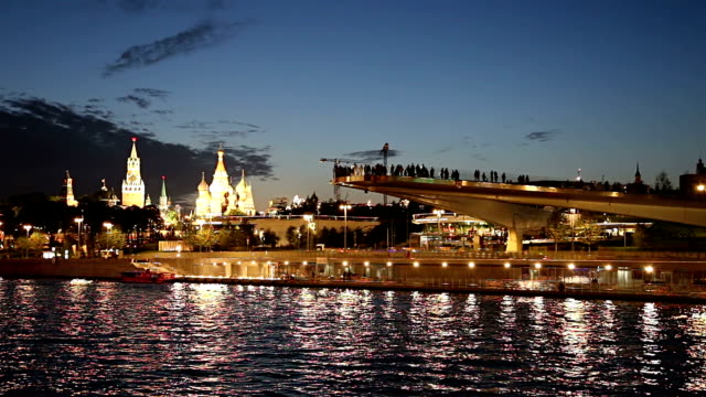 Schwimmende-Brücke-von-Zaryadye-Park-auf-Moskvoretskaya-Embankment-des-Flusses-Moskva-(und-touristisches-Vergnügungsboot)-bei-Nacht.-Moskau,-Russland.