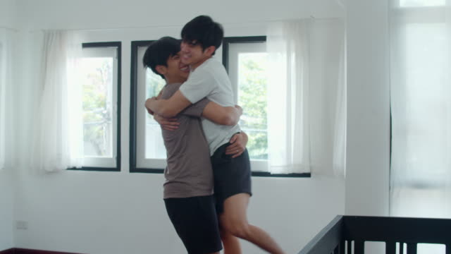 Young-Asian-Gay-couple-feeling-funny-active-having-fun-dancing-together-at-home.-Cheerful-Asia-LGBTQ+-men-enjoy-moving-to-music-spending-weekend-time-in-living-room-at-modern-house-in-morning-concept.