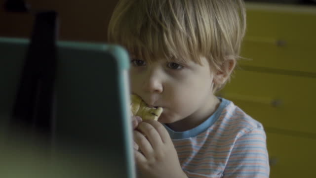 kleiner-Junge-essen-beim-Anschauen-digitaler-Tablet