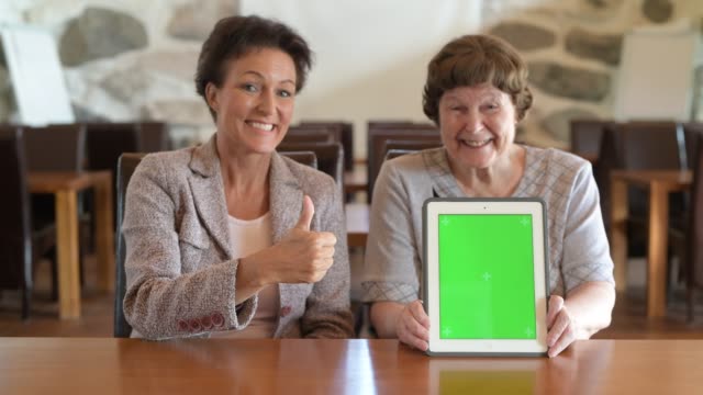Happy-Mother-And-Daughter-Showing-Digital-Tablet-Together-And-Giving-Thumbs-Up