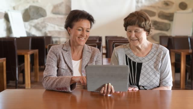 Glückliche-Mutter-und-Tochter-mit-digitalem-Tablet-zusammen-im-Coffee-Shop