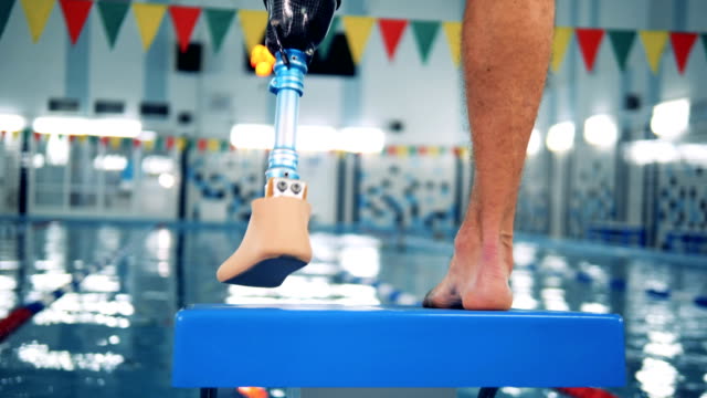 Swimming-pool-and-a-male-with-a-robotic-leg-standing.