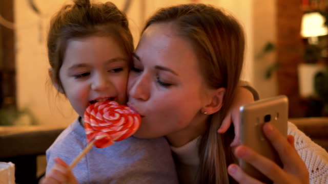 Tochter-mit-Mama-machen-Selfie-essen-herzförmige-Süßigkeiten
