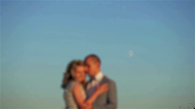 Man-and-woman-blurred-stand-embracing-at-moon-in-sky-background.-Couple-unfocused-silhouetted-kiss-holding-at-shining-lunar-disk-shining-in-clear-sky-space.-Planning-pregnancy-moon-phase-cycles-fertility