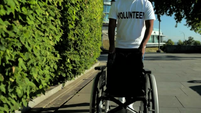Slow-Motion-eines-angenehmen-Freiwilligen-schieben-eines-Rollstuhls