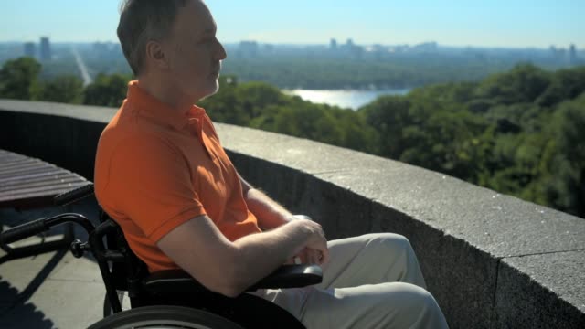 Hombre-pensativo-wheelchaired-disfrutando-de-las-vistas-de-la-ciudad