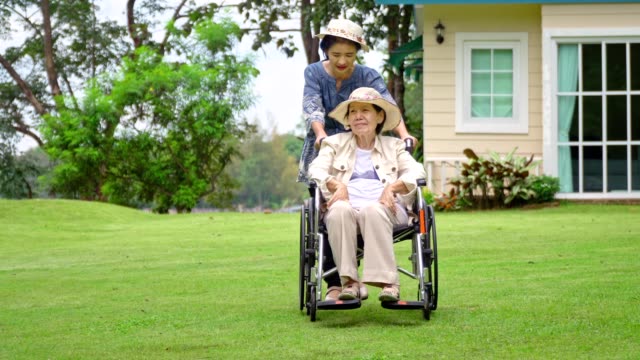 Mujer-mayor-relajación-en-silla-de-ruedas-en-el-patio-trasero-con-hija