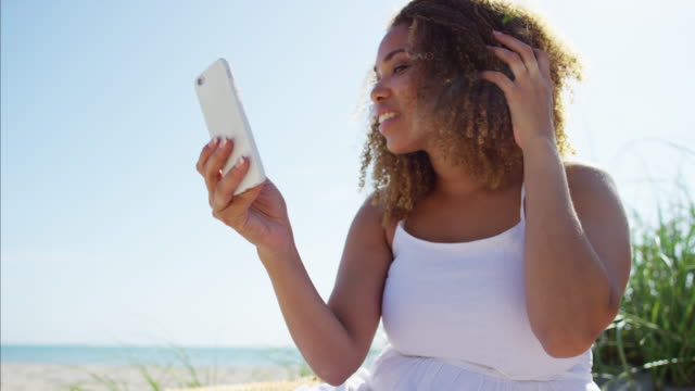 Mujer-afroamericana-con-teléfono-inteligente-en-la-playa