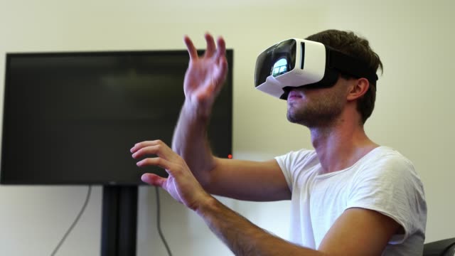 Junger-Mann-mit-VR-virtual-Reality-Kopfhörer-Brille-auf-dem-Kopf-in-der-Geschäftsstelle.