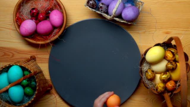 Child's-hand-lays-colored-easter-eggs-in-different-baskets