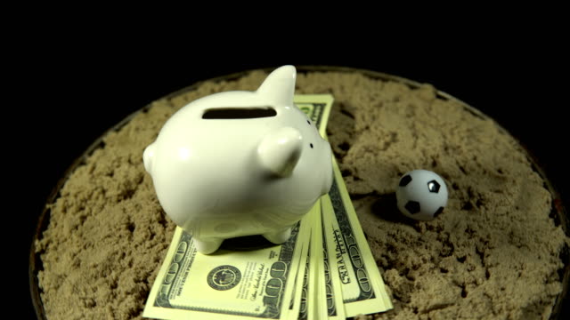 Ein-weißes-Sparschwein-und-Dollar-Rechnungen-Spins-auf-einem-schwarzen-Hintergrund.