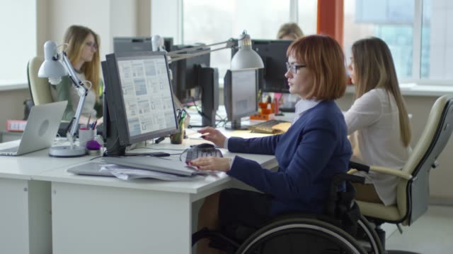 Querschnittsgelähmt-geschäftsfrau-im-Rollstuhl-am-Schreibtisch-im-Büro-arbeiten
