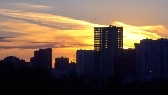 Blick-auf-die-Stadt-bei-Sonnenuntergang-mit-einem-Flugzeug-fliegen-am-Horizont