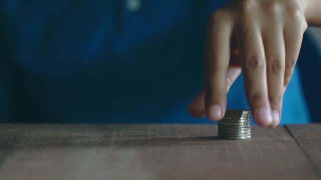 Woman-stacking-coins-on-a-wooden-table.