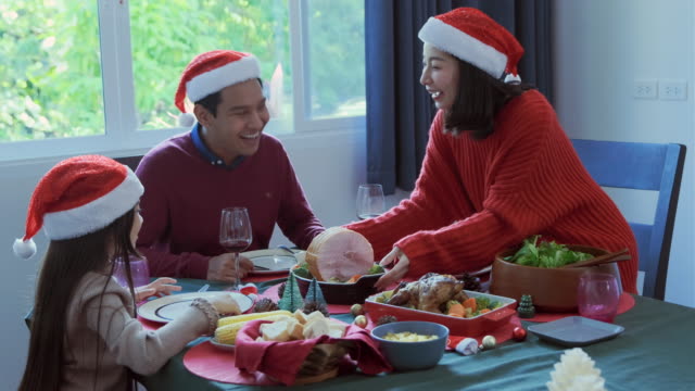 Asiatische-glückliche-Familie-mit-Mahlzeit-zusammen-im-Speisesaal,-der-mit-Weihnachtsbaum-geschmückt