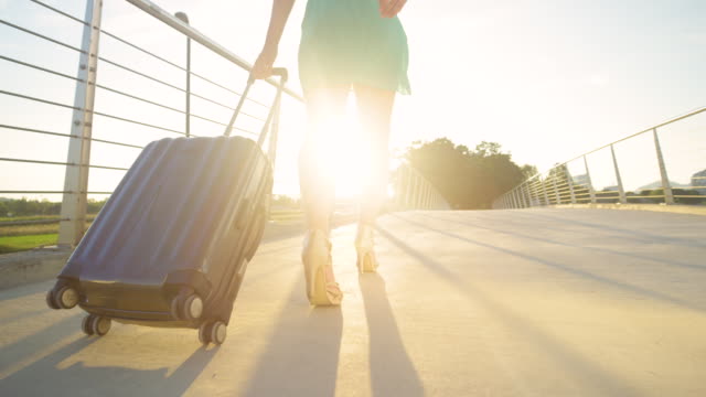BAJO-ANGLE:-La-joven-está-arrastrando-su-maleta-al-aeropuerto-con-tacones-altos