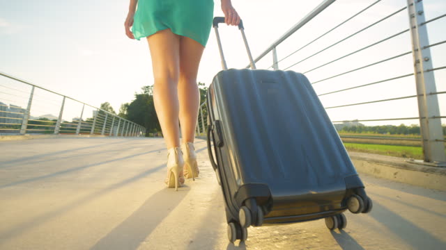 ANGLE-BAJO:-Puesta-de-sol-dorada-brilla-en-la-turista-femenina-en-su-camino-al-aeropuerto.