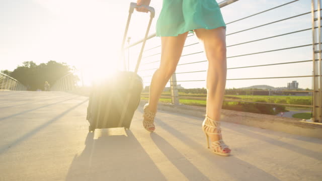 CLOSE-UP:-Gorgeous-woman-in-heels-walks-across-an-overpass-with-a-suitcase.