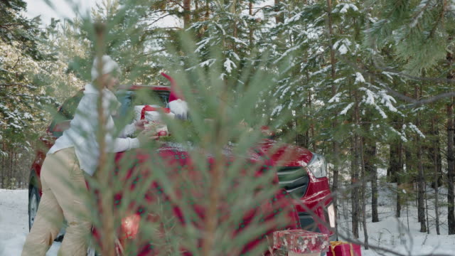 Hermosa-mujer-sosteniendo-regalo-de-Navidad-sobre-el-fondo-del-coche-rojo-en-el-bosque-nevado.-Mujer-adulta-con-regalo-de-Año-Nuevo-cerca-de-coche-rojo-en-el-bosque-nevado-en-las-vacaciones-de-invierno.