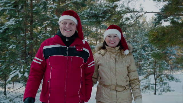Winterpaar-in-Weihnachtsmütze-zu-Fuß-auf-verschneiten-Wald.-Paar-in-liebe-Mann-und-Frau-zu-Fuß-auf-verschneiten-Wald-im-Winterurlaub.-Neujahrsspaziergänge-im-Wald.