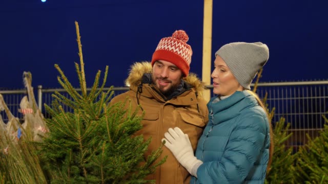 happy-couple-buying-christmas-tree-at-market