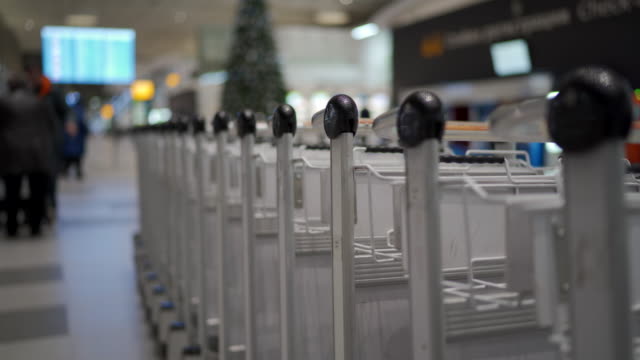 Row-of-luggage-carts-at-airport-terminal,-airport-baggage-trolley-parking-lot
