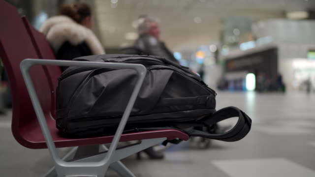 Reiserucksack-auf-Bank-im-Wartebereich-des-Flughafenterminals-mit-Stühlen