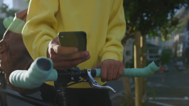Transgender-adult-with-a-bike-and-using-a-phone
