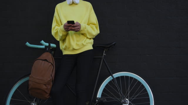 Adulto-transgénero-con-una-bicicleta-y-el-uso-de-un-teléfono