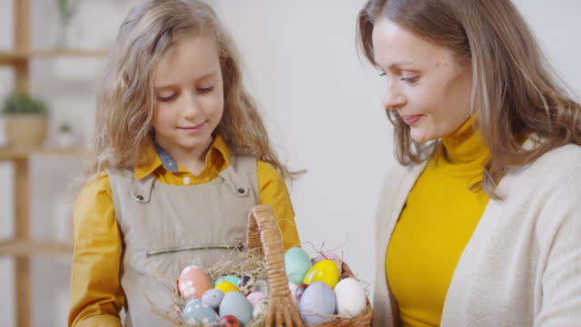 Mujer-feliz-y-chica-posando-con-huevos-de-Pascua