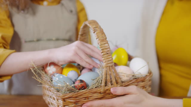 Irreconocible-niña-y-mujer-sosteniendo-cesta-de-huevos-de-Pascua
