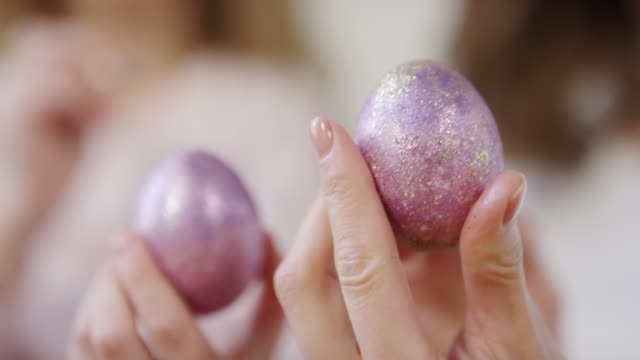 Manos-sosteniendo-huevos-de-Pascua-decorados-con-pintura-brillante
