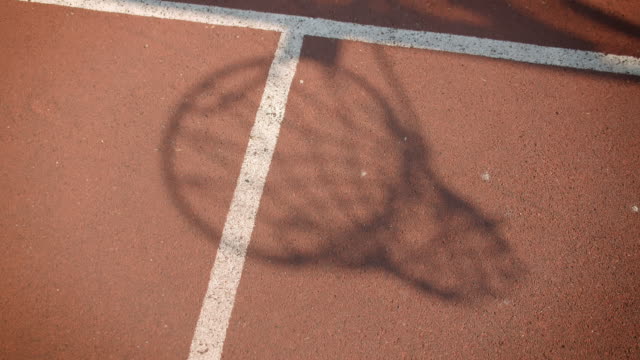 Closeup-portrait-of-shadow-of-basketball-ball-being-thrown-into-a-hoop-outdoors-on-the-court