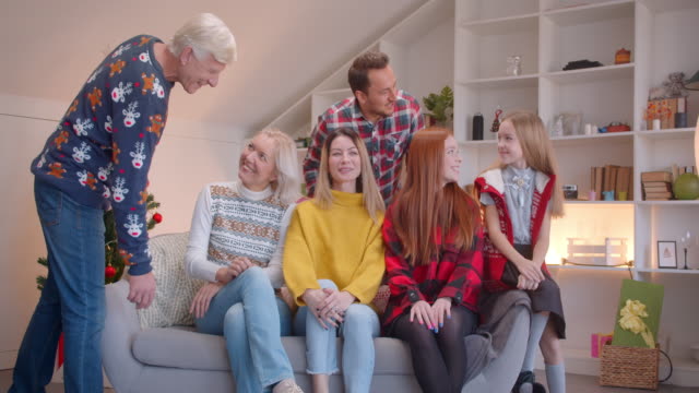 Gran-familia-se-está-preparando-para-un-retrato-en-el-sofá-de-Navidad-aplaudiendo-sonriendo-feliz