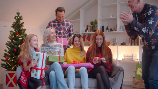Große-Familie-freut-sich-über-Weihnachtsgeschenke-sitzend-auf-einem-Sofa-lächelnd-lachenden-Komfort