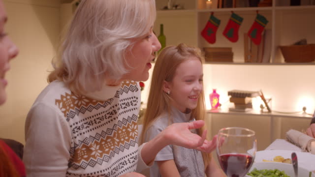Großmutter-mit-Enkelinnen-Weihnachten-Abendessen-Kindheit-Freude-Geschenke-Freude-Glück-Lächeln