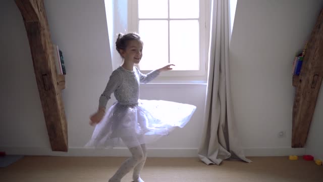 Little-girl-with-magical-light-jumping-around-in-circles-having-fun-and-playing.-Sweet-joyful-blonde-kid-dancing-in-her-bedroom-dressed-with-ballerina-dress.-Happy-lifestyle-with-children-at-home.