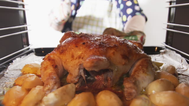 Woman-cooking-whole-roasted-chicken-baked-in-oven,-crispy-chicken-and-vegetables