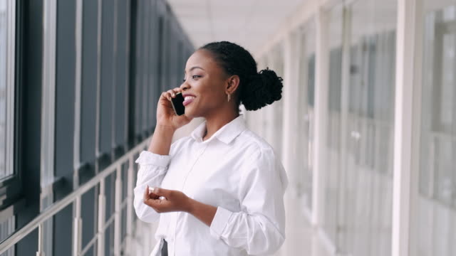 Afroamerikanische-Frau-telefoniert-und-lächelt-am-Flughafen