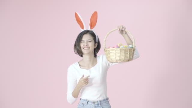 Cheerful-happy-girl-wear-bunny-ears,-hold-a-basket-with-Easter-eggs-colorful-joyful,-spinning-around-and-show-basket-forward-to-camera.-Funny-bunny-girl-in-Easter.The-symbolic-of-Easter-egg-festival.