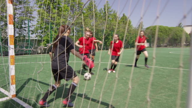 Jugadoras-de-fútbol-femeninos-anotando-gol-durante-el-partido-al-aire-libre
