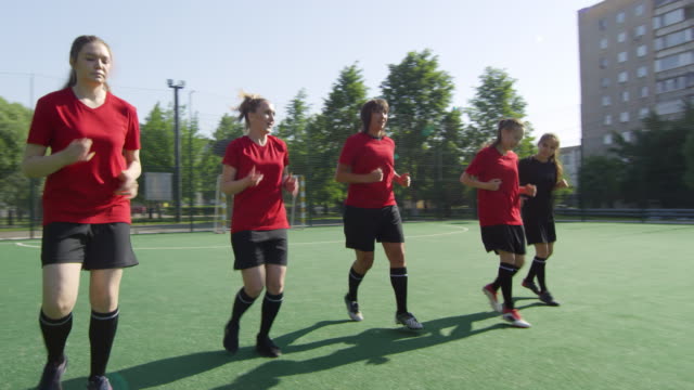 Weibliche-Fußballsportlerlaufen-rückwärts-auf-dem-Feld
