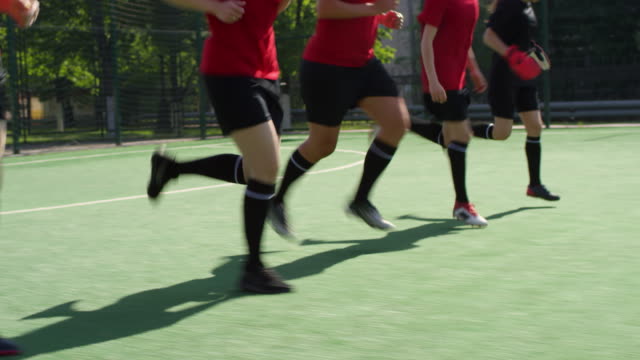 Atletas-de-fútbol-femeninohaciendo-levantamiento-de-talón-corriendo