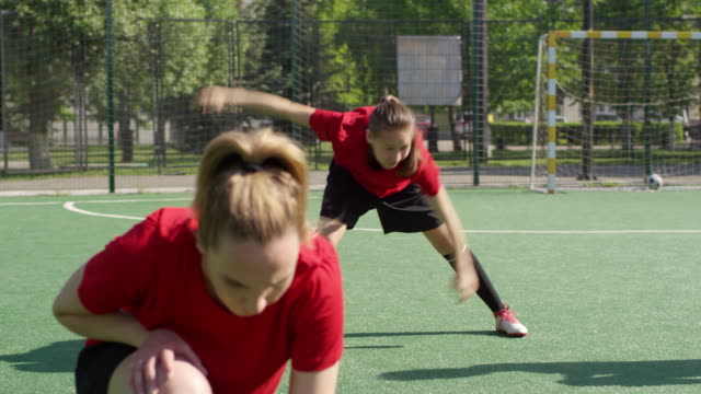 Jóvenes-jugadoras-de-fútbol-femeninas-haciendo-estiramientoen-en-el-campo