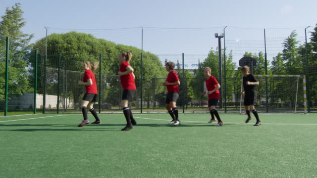 Weibliche-Fußballsportler-üben-seitlichen-Lauf-auf-dem-Feld-während-des-Trainings