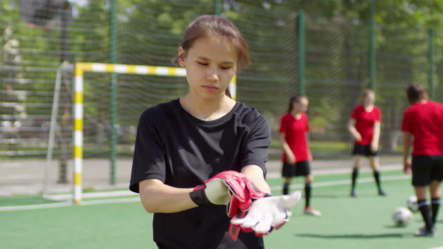 Joven-jugadora-de-fútbol-femenina-poniéndose-guantes-de-portero