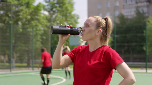 Young-Female-Soccer-Player-Drinking-Water-on-Field